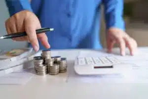 mano-sujetando-lapicero-apunto-de-tomar-unas-monedas